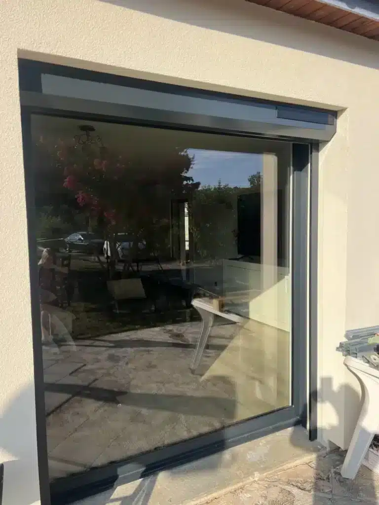 Baie vitrée à galandage avec volet roulant solaire gris anthracite installée à Charantonnay par 1001 Fenêtres - menuiserie Isère 38